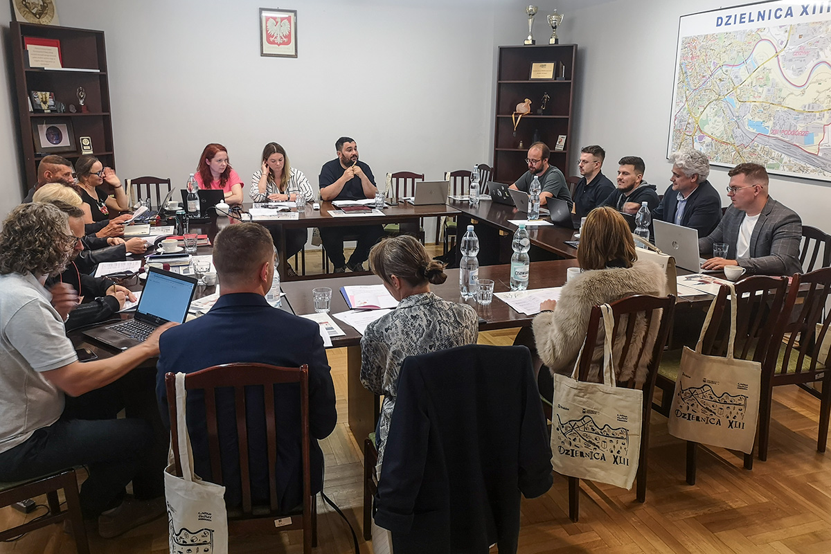 zdjęcie z sesji - radni siedzący przy stołach ustawionych w duży kwadrat