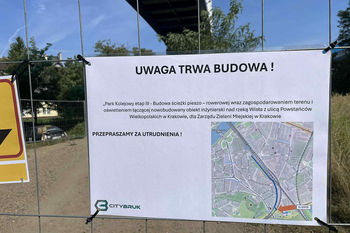 tablica z informacją o remoncie, w tle teren parku